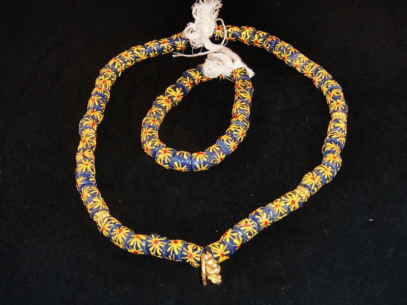 Blue with hand-painted multi-colored starburst pattern & golden accents; on string / tie-on; neck beads approx. 25" long; wrist beads approx. 10 1/2" long.
